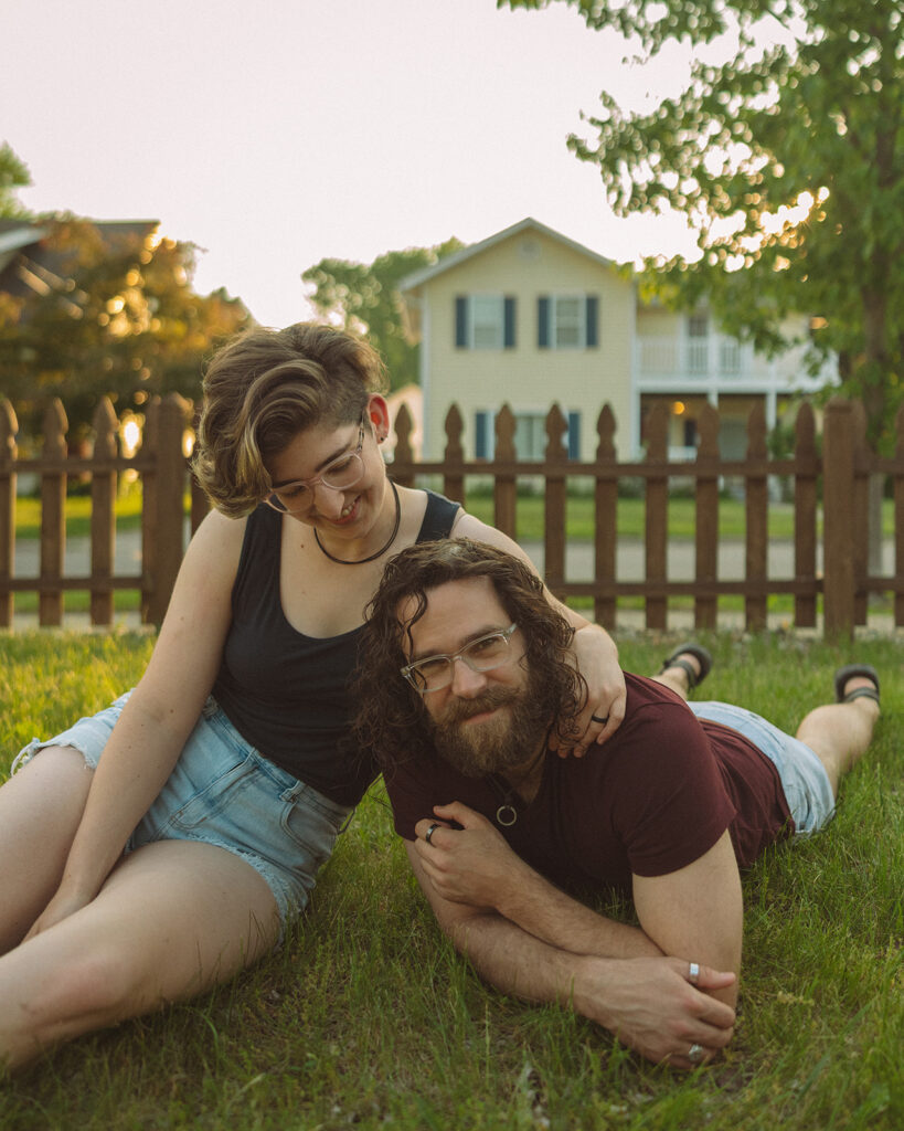 Couple posing in their front yard for their casual outdoor Michigan engagement photos