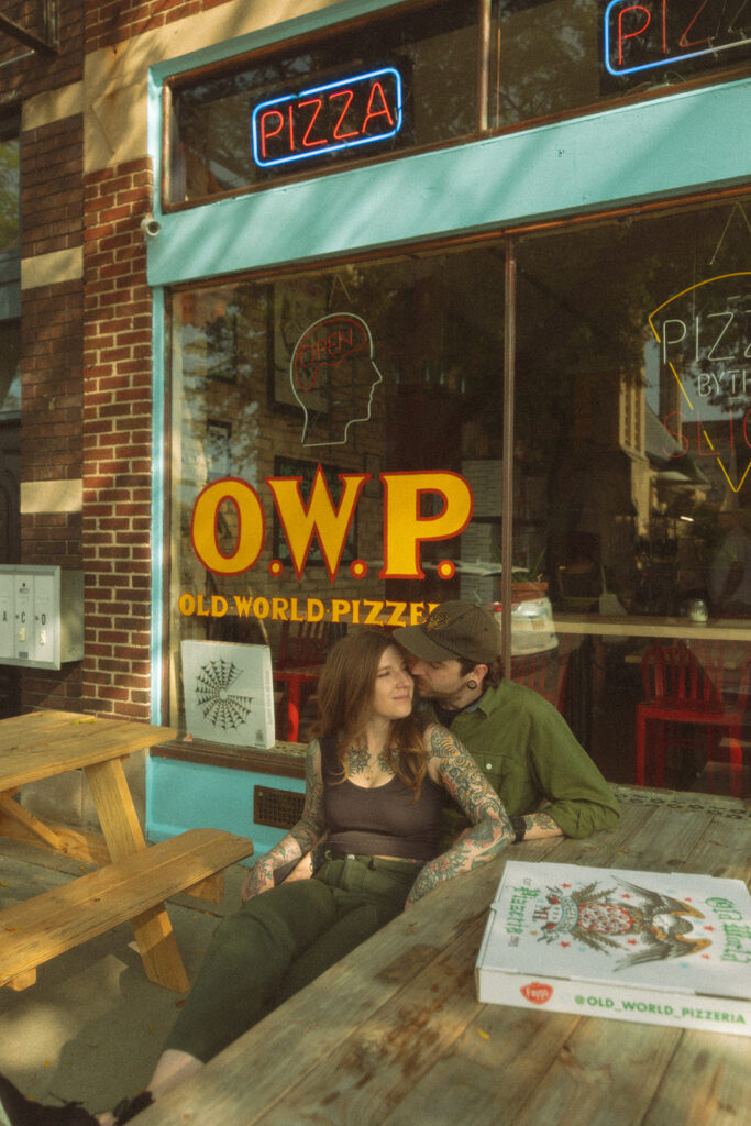 Couple cuddled up on a picnic table outside of Old World Pizzeria in Saginaw, Michigan for their casual low-key engagement session.