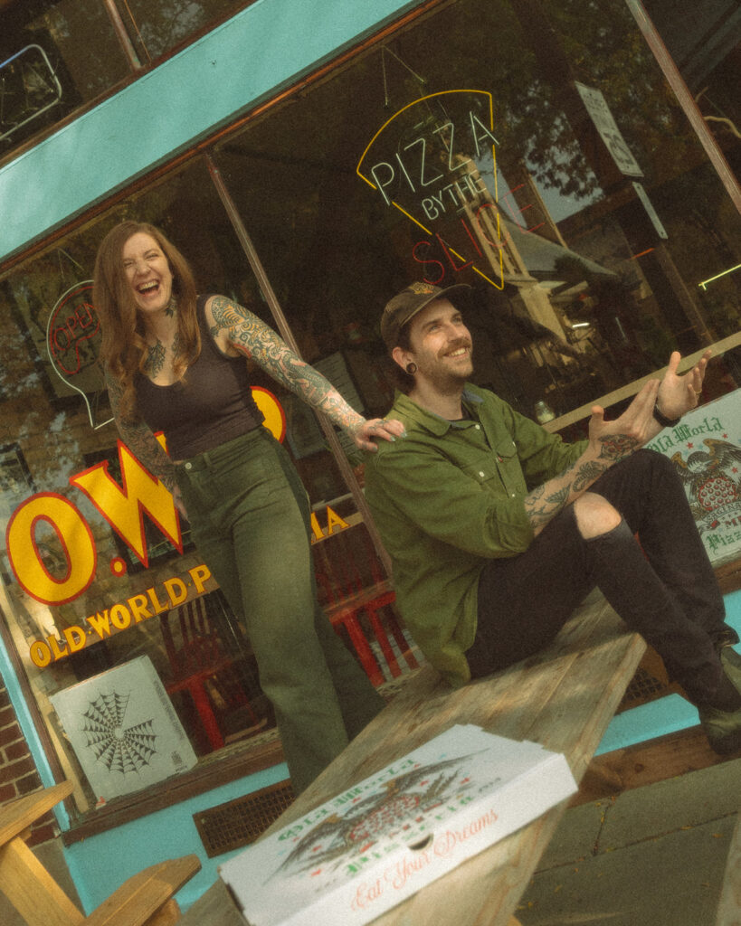 Couple laughing during their casual low-key engagement session outside of Old World Pizzeria in Saginaw, Michigan.