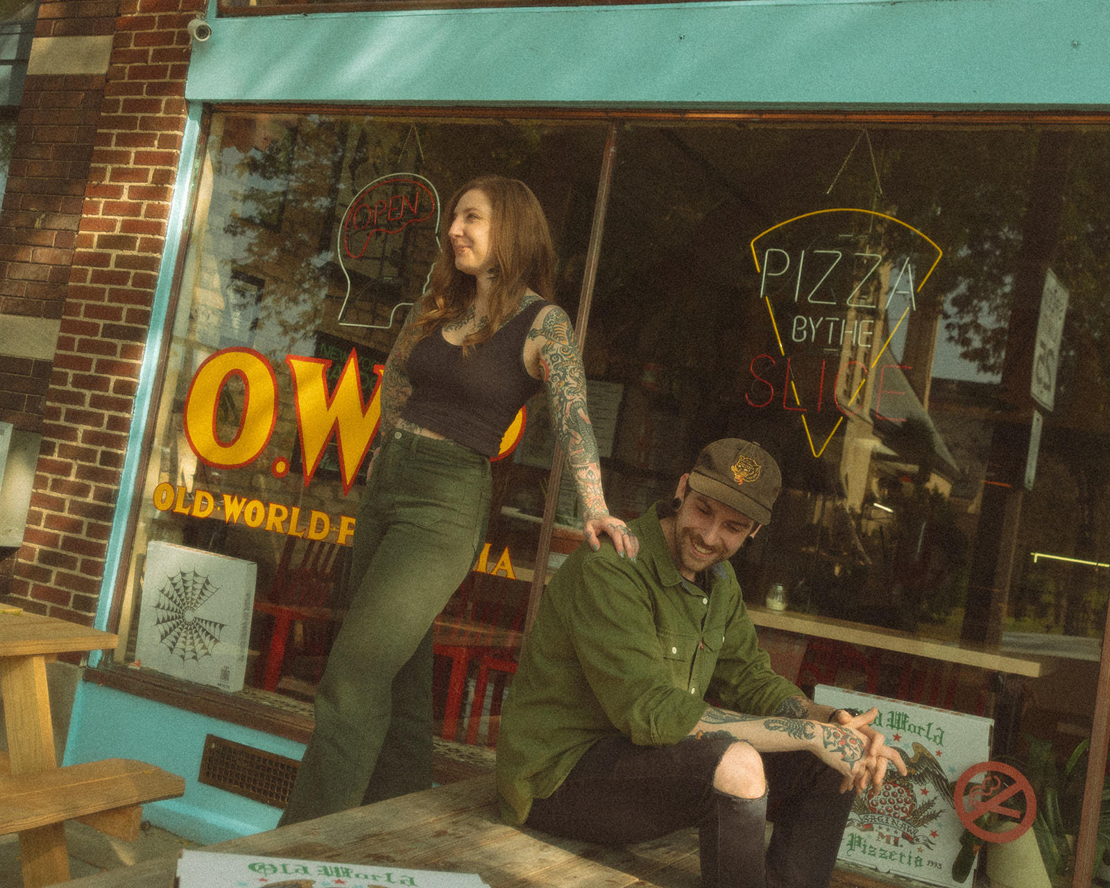 Couple posing on a picnic table at Old World Pizzeria in Saginaw, Michigan for their casual low-key engagement session.
