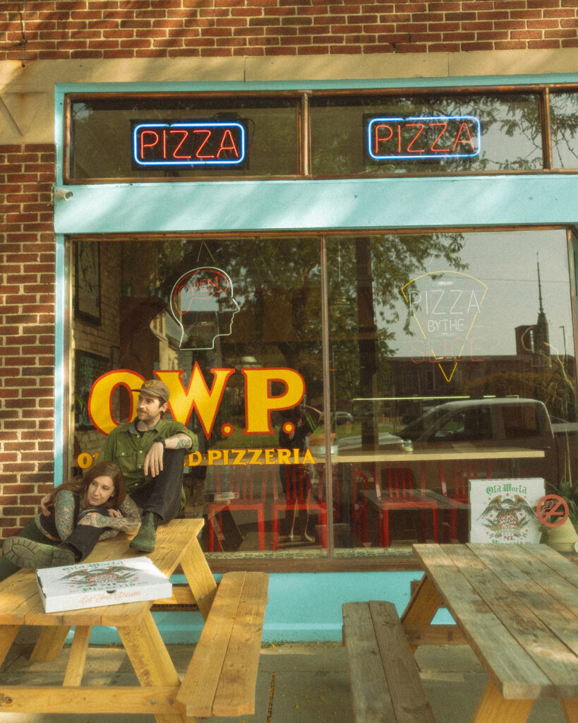 Couple posing outside of Old World Pizzeria in Saginaw, Michigan for their casual low-key engagement session.