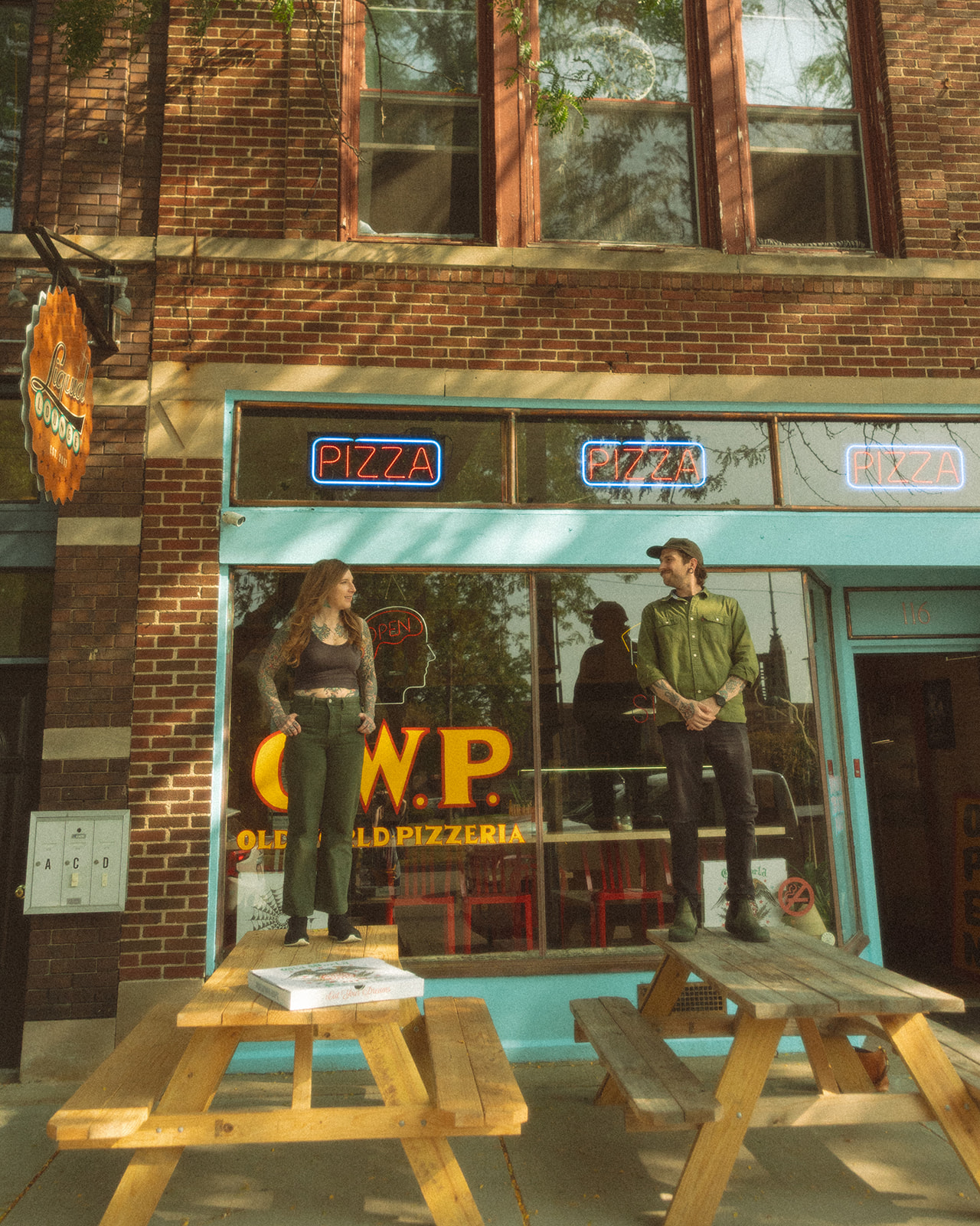 Couple standing on picnic tables outside of Old World Pizzeria in Saginaw, Michigan for their casual low-key engagement session.