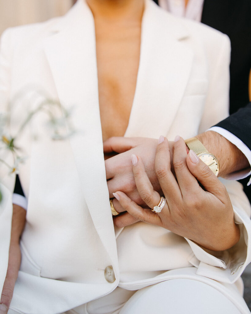 Close up shot of a bride and groom holding hands.