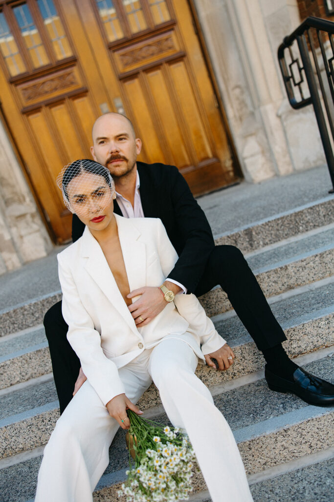 Editorial elopement portrait of a bride and groom sitting on the stairs at Birmingham City Hall.