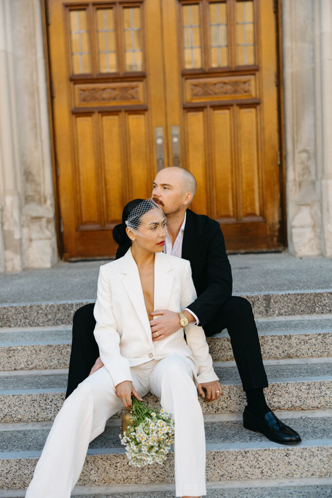 Editorial elopement portrait of a bride and groom sitting on the stairs at Birmingham City Hall.