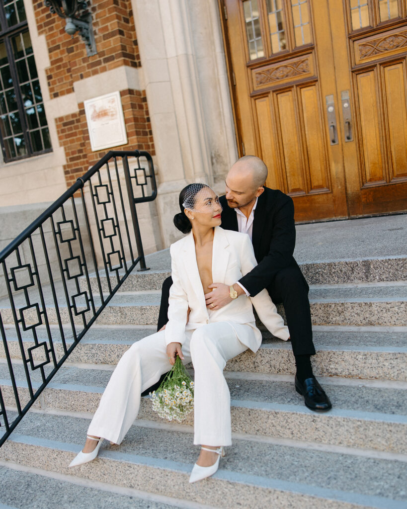 Editorial elopement portrait of a bride and groom sitting on the stairs at Birmingham City Hall.
