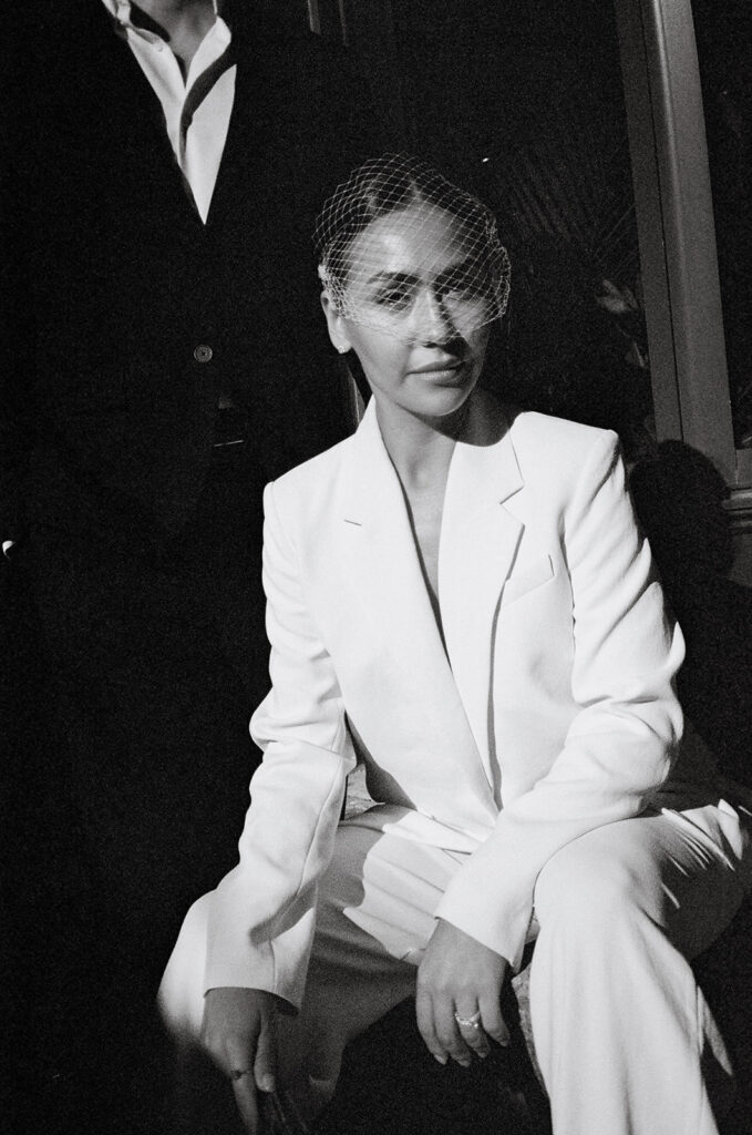 Black and white film photo of a bride and groom posing on the Detroit People Mover. 