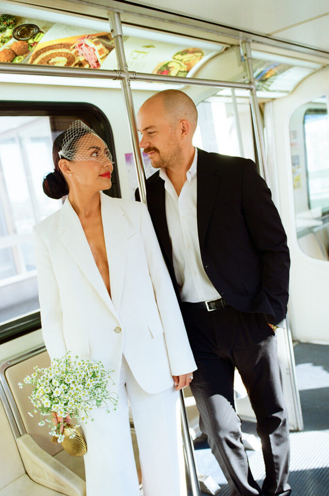 Bride and groom looking at each other as they post for their Detroit elopement photos on the People Mover on film.