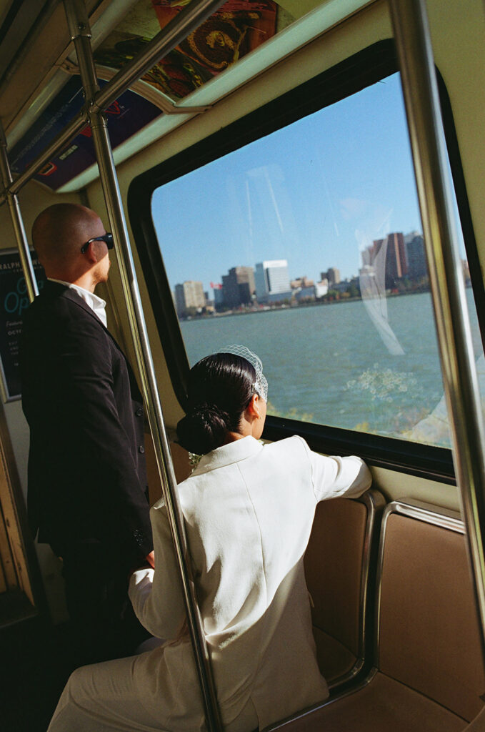 Film photo of a bride and groom looking out at the city on the Detroit People Mover during their elopement.