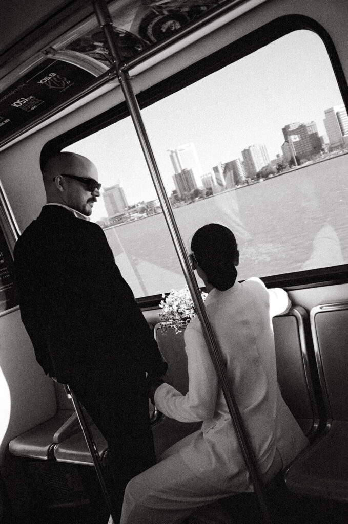 Black and white film photo of a couple looking at the city while on the Detroit People Mover. 