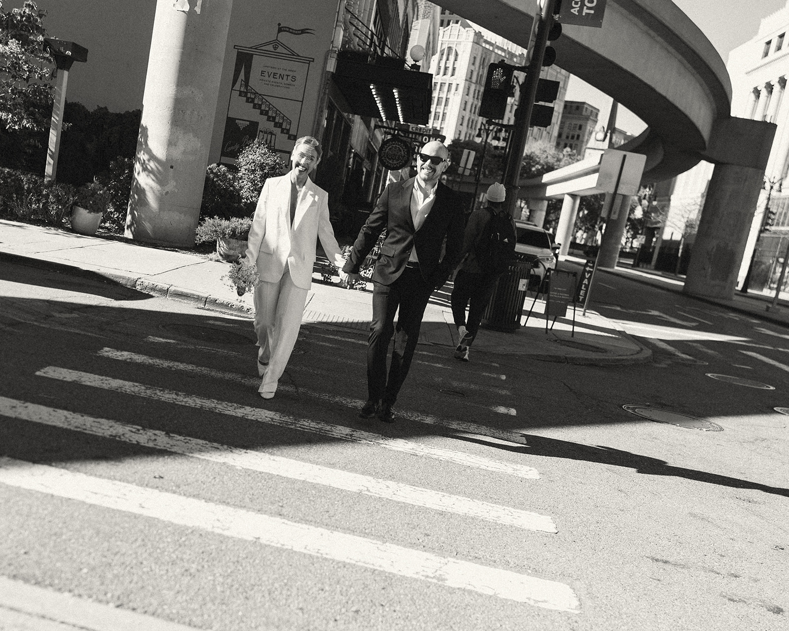 Black and white photo of a couple walking across the street for their Detroit elopement photos. 