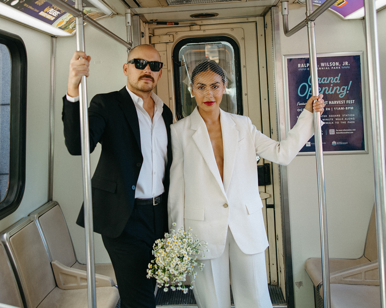 Bride and groom standing inside the Detroit People Mover holding poles during their city elopement portraits.