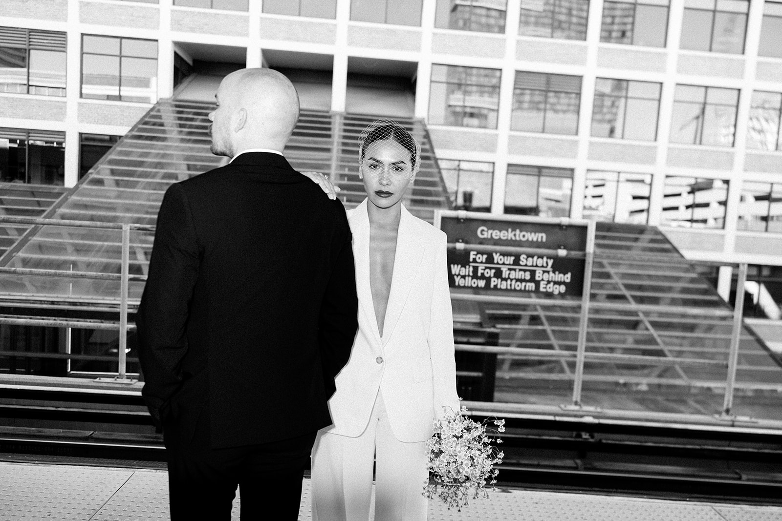 Black and white photo of a couple posing in from of Greektown sign downtown. 