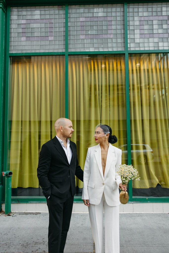 Couple posing in front of a green window backdrop for their downtown Detroit elopement photos.