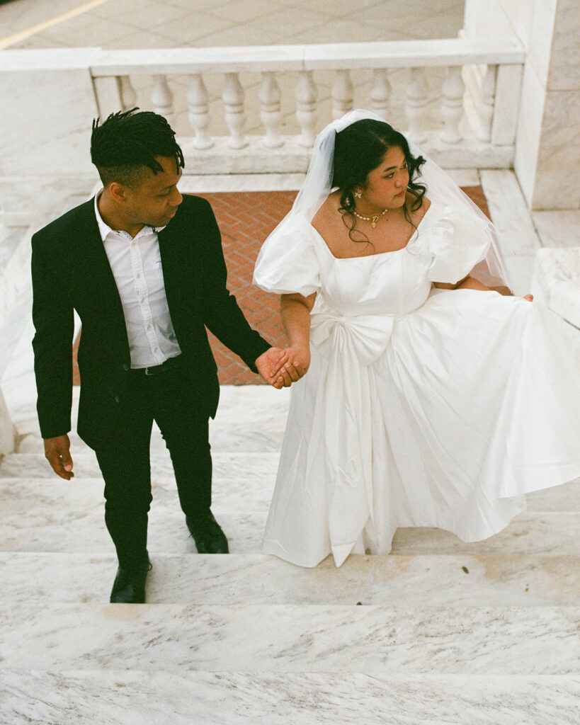 Couple holding hands and walking up a staircase for their film Michigan wedding photography.