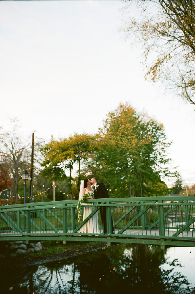 Bride and groom kissing on a bridge during their Michigan film wedding photography.