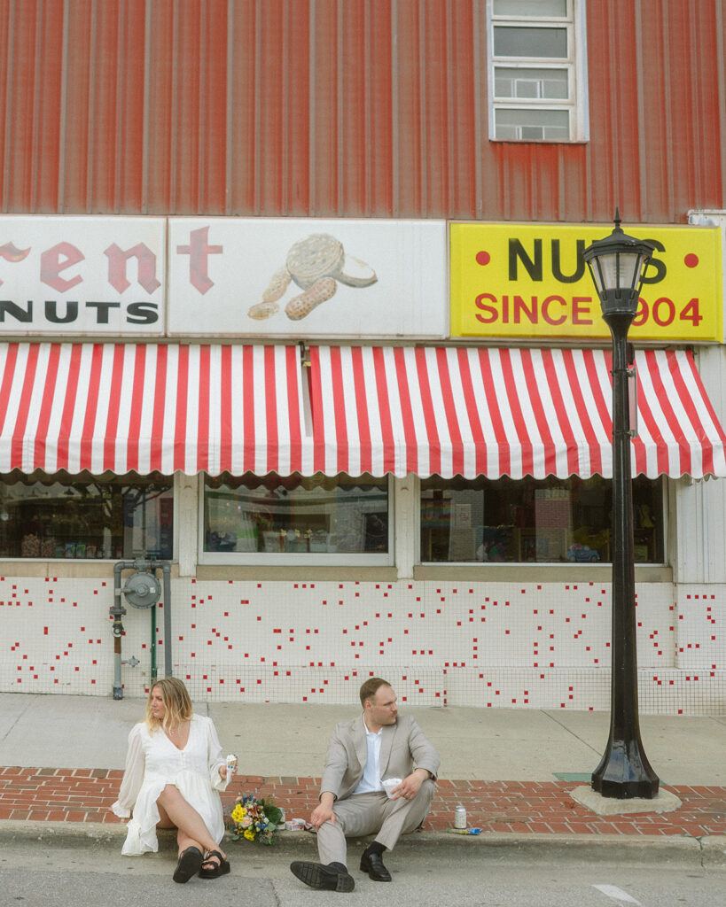 Couple sitting outside of a store on a sidewalk during their Michigan elopement photoshoot. 