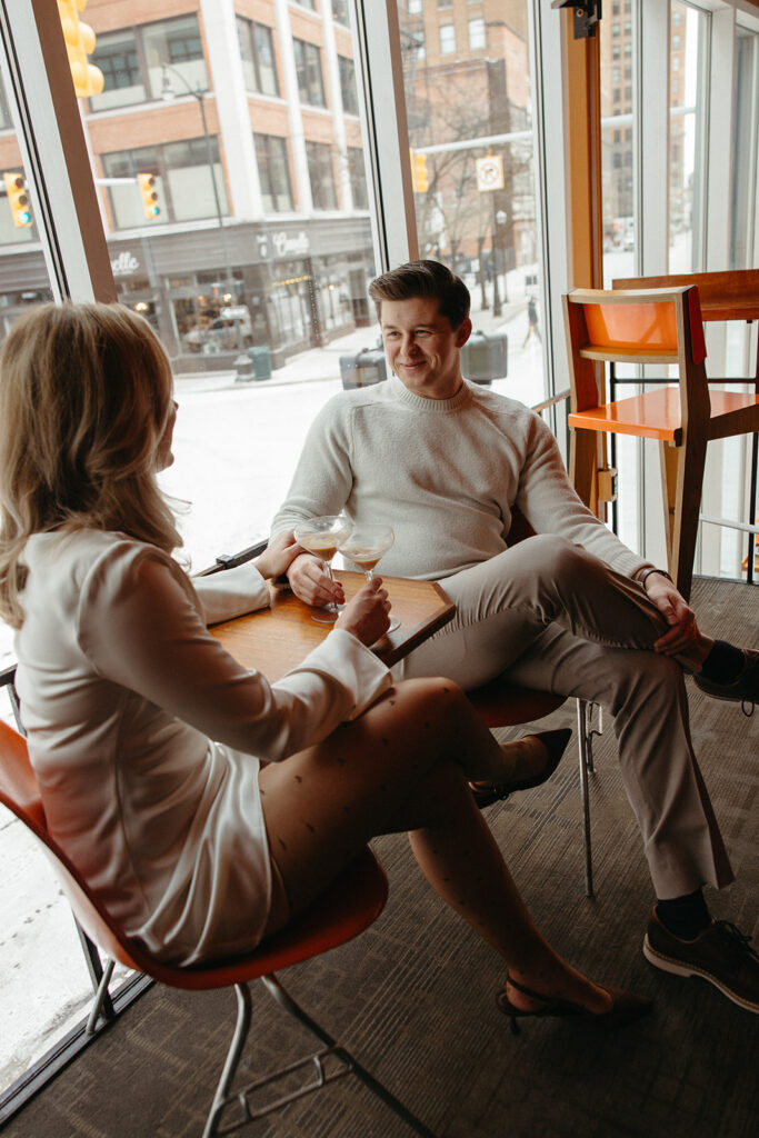 Couple having drinks and talking during their downtown Detroit engagement photos at SPKRBOX.