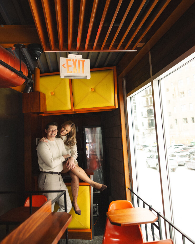 Couple smiling together inside SPKRBOX near neon yellow panels during Detroit engagement photos in downtown Detroit.
