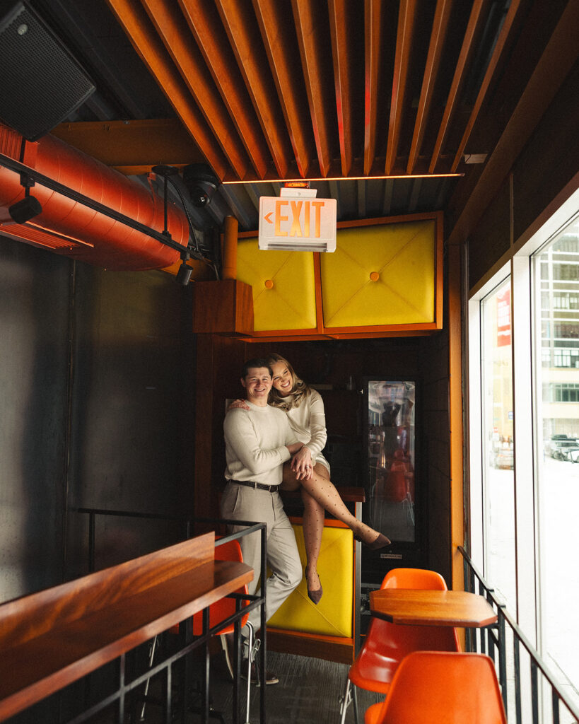 Couple posing together inside SPKRBOX near neon yellow panels during Detroit engagement photos in downtown Detroit.