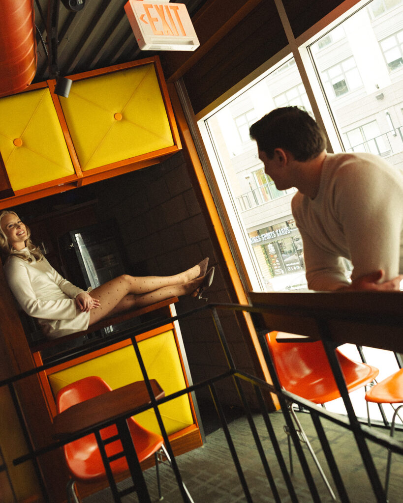 Couple posing inside SPKRBOX near neon yellow panels during Detroit engagement photos in downtown Detroit.