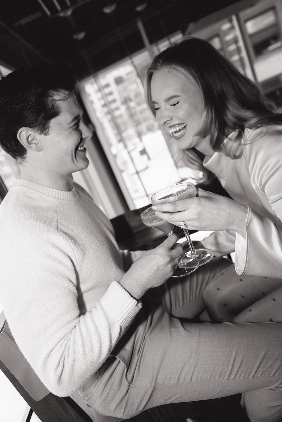 Black and white photo of couple laughing together inside SPKRBOX during Detroit engagement photos.