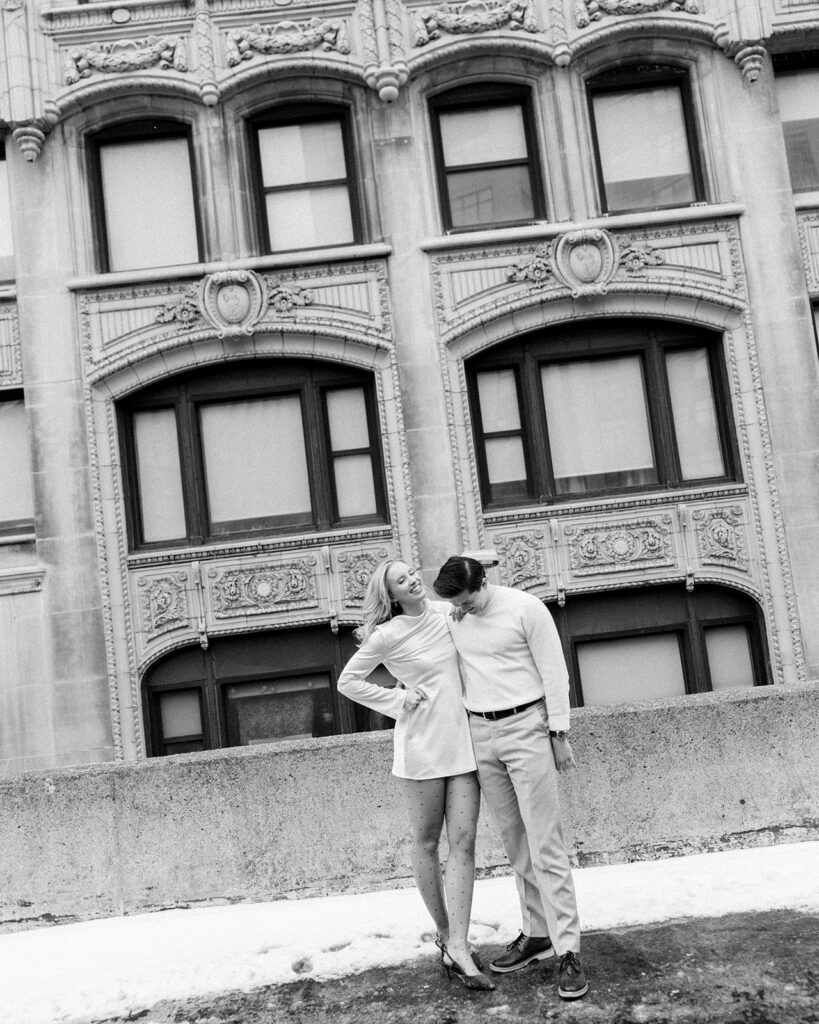 Black and white photo of a couple posing on a Detroit rooftop for their engagement session.