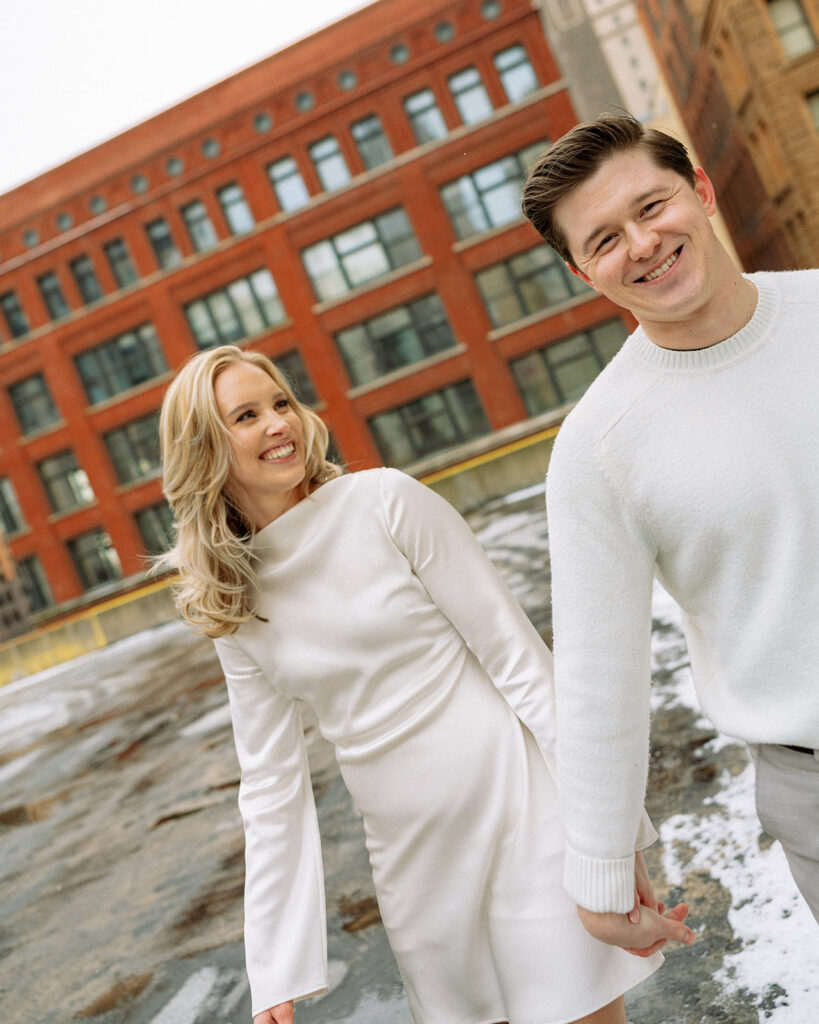 Couple holding hands and walking on a rooftop in Detroit.