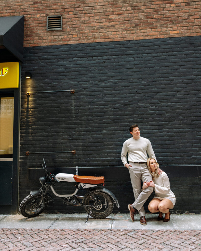 Couple posing next to a motorcycle in a downtown Detroit alleyway.