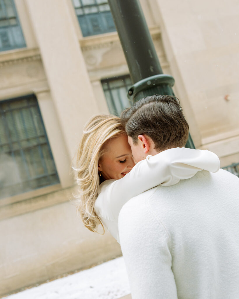 Couple standing together by a streetlight in downtown Detroit during winter.