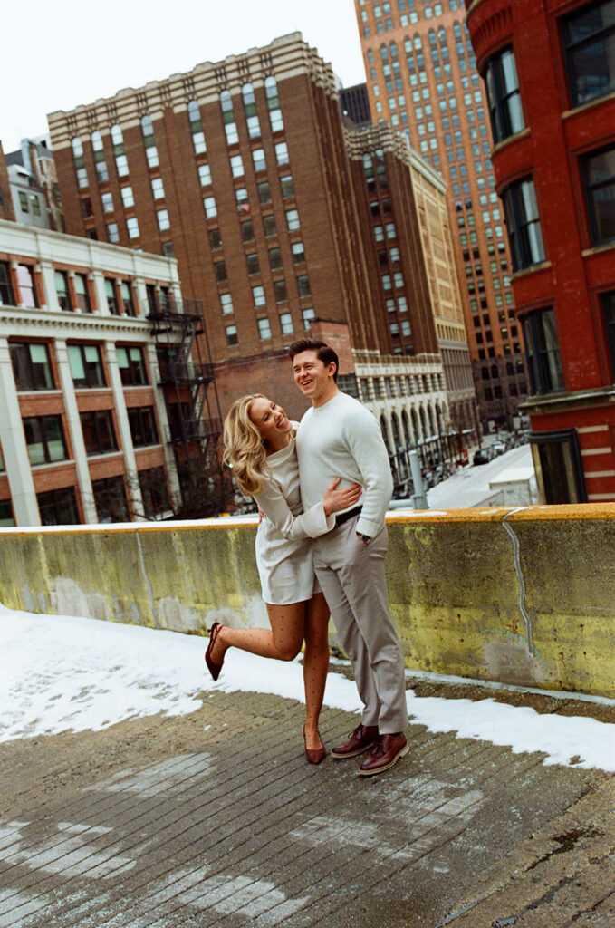 Couple embracing on a snowy rooftop in downtown Detroit, captured on film.