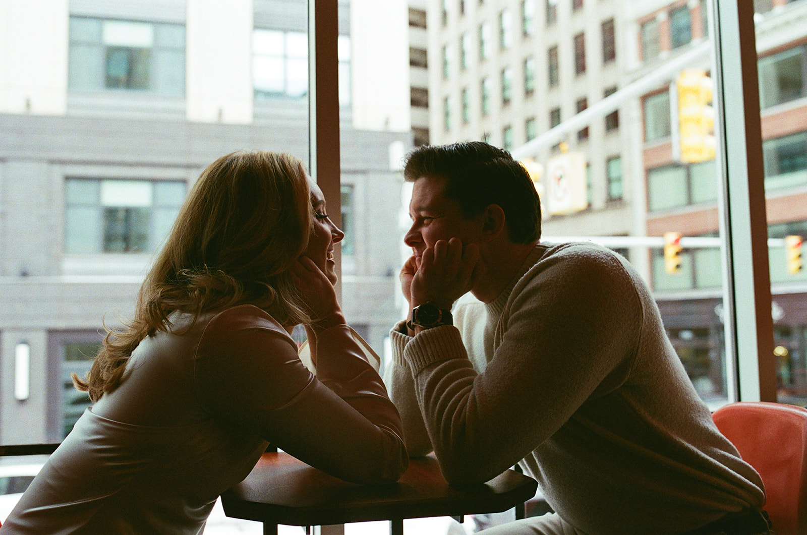 Film photo of a couple sitting at a table during their downtown Detroit engagement photos.