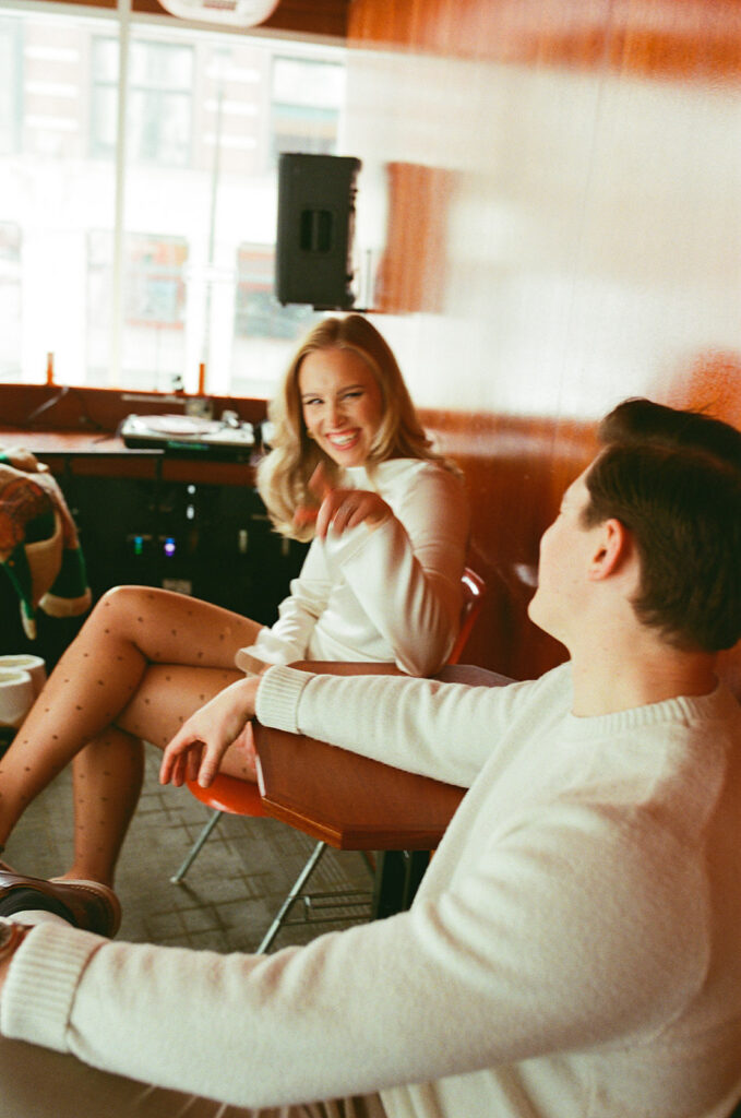 Couple laughing together at a table inside of SPKRBX in Detroit, captured on film.
