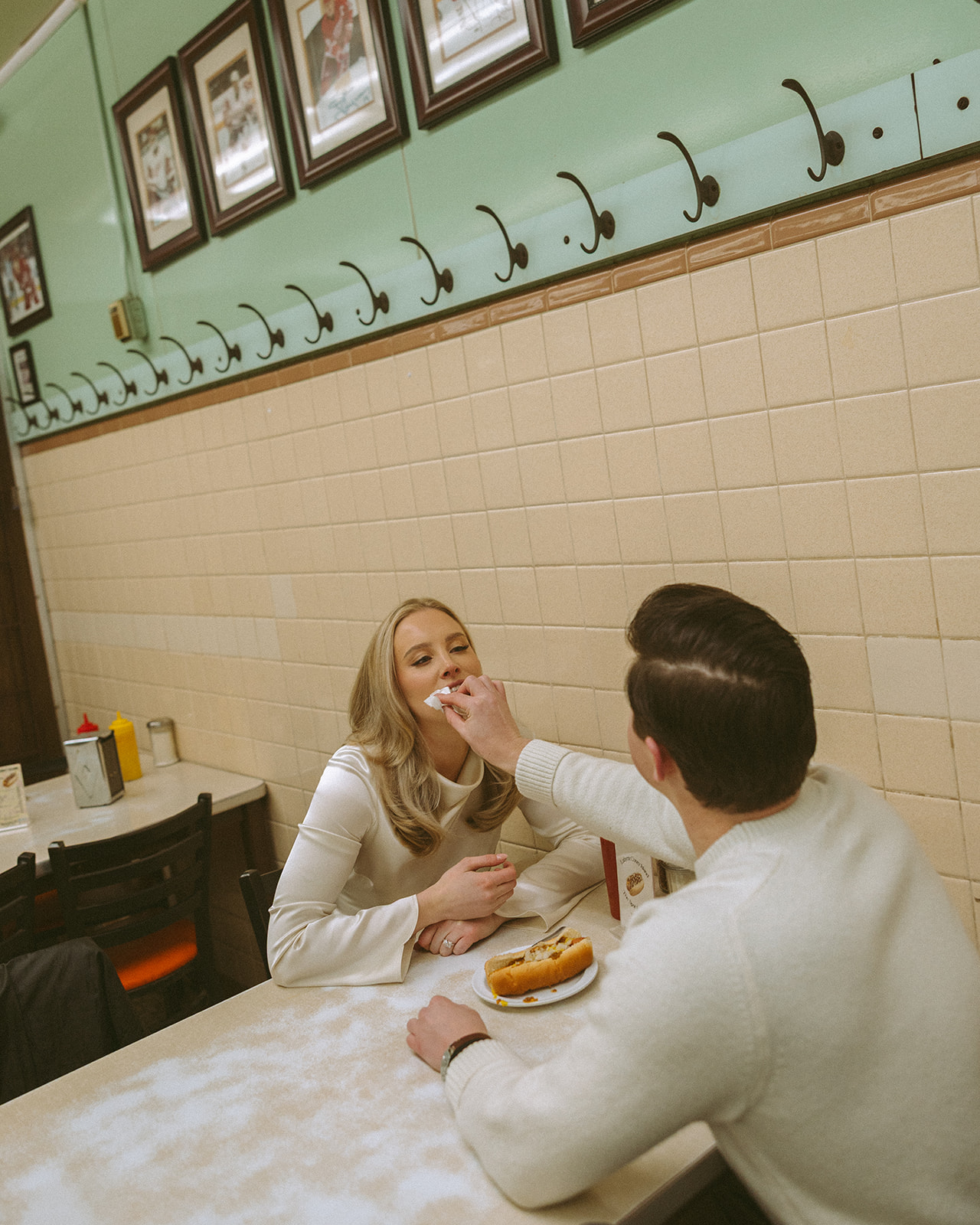 Man wiping his fiancés mouth while sitting at a table inside Lafayette Coney Island.