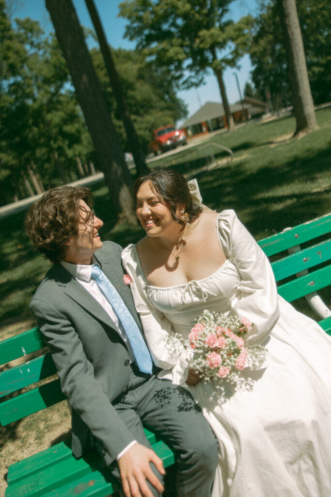 Couple sitting on a park bench together after their Michigan elopement.