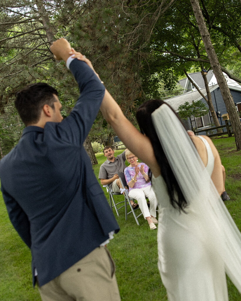 Bride and groom holding their hands up in the arm in celebration after their intimate Michigan micro wedding ceremony.