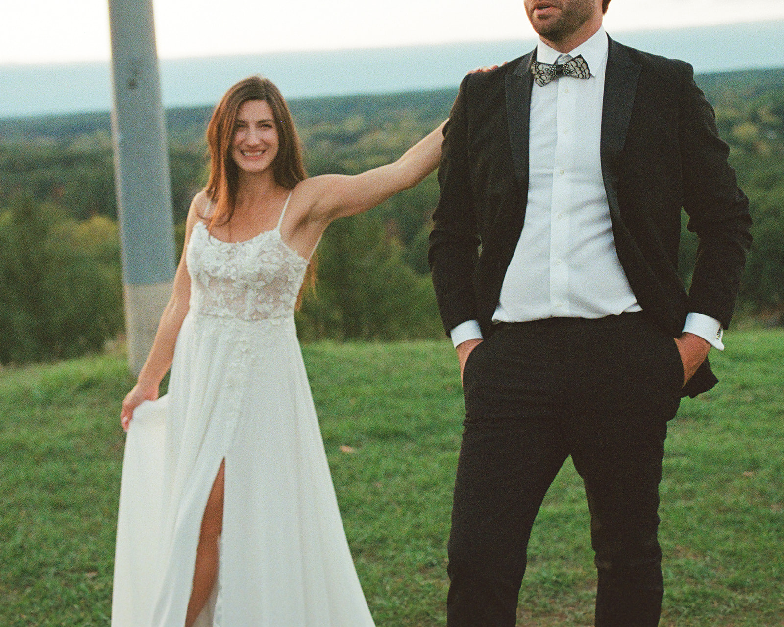 Bride smiling and holding dress while walking outdoors during relaxed documentary wedding portraits in Michigan on film.