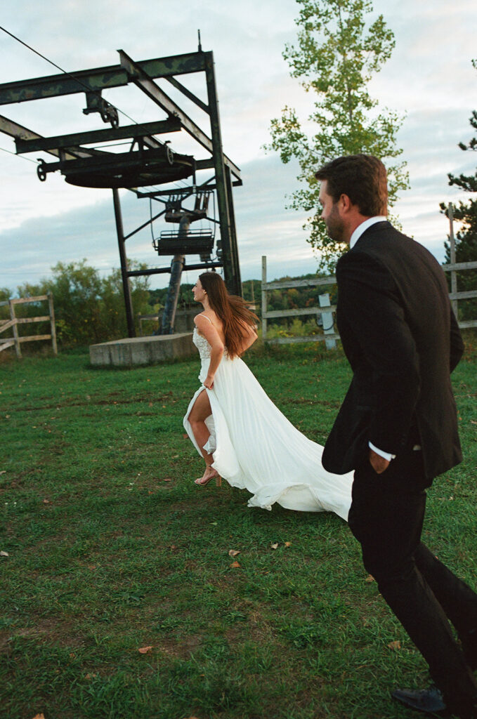 Documentary Michigan wedding photo of a couple running in the grass.