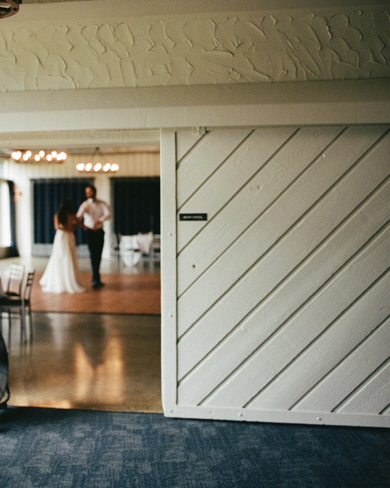 Bride and groom softly dancing in the background of a reception space before the wedding day begins.