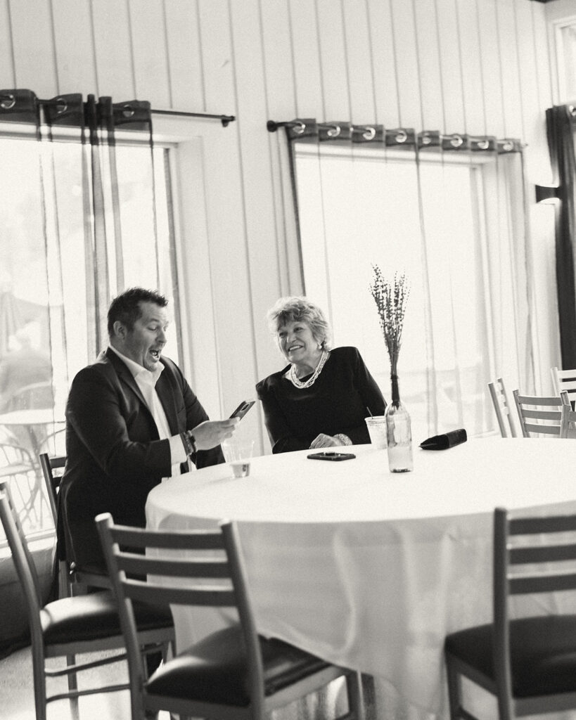 Two guests sitting at a wedding reception table and talking. 