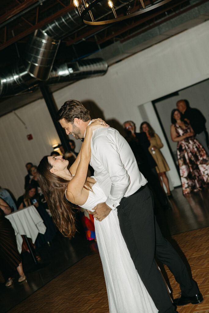 Bride and groom dancing during first dance at indoor wedding reception.