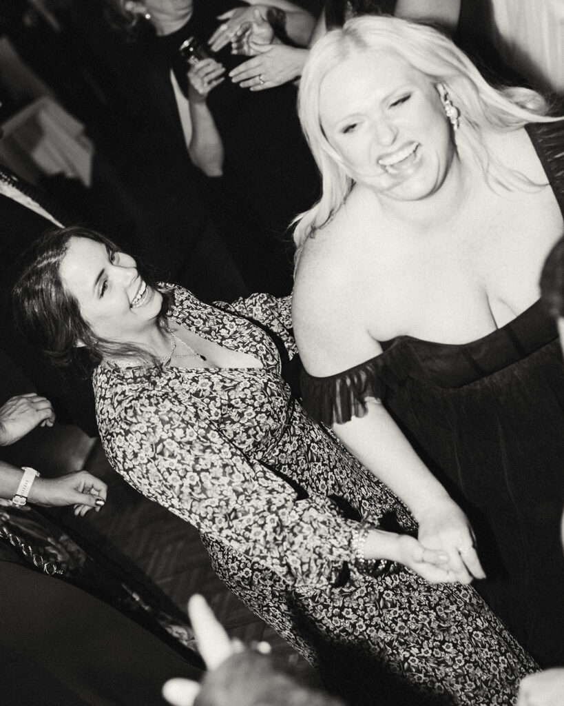 Black and white photo of guests laughing during the reception.
