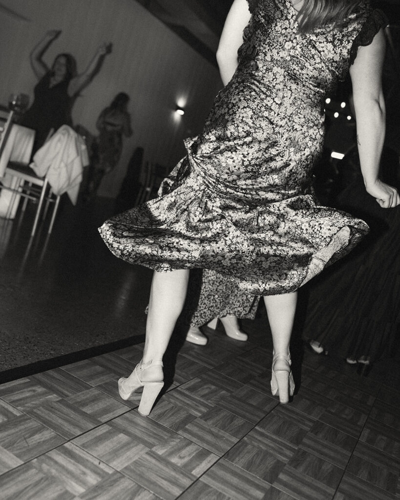 Black and white photo of a guest twirling in her dress on the dance floor.