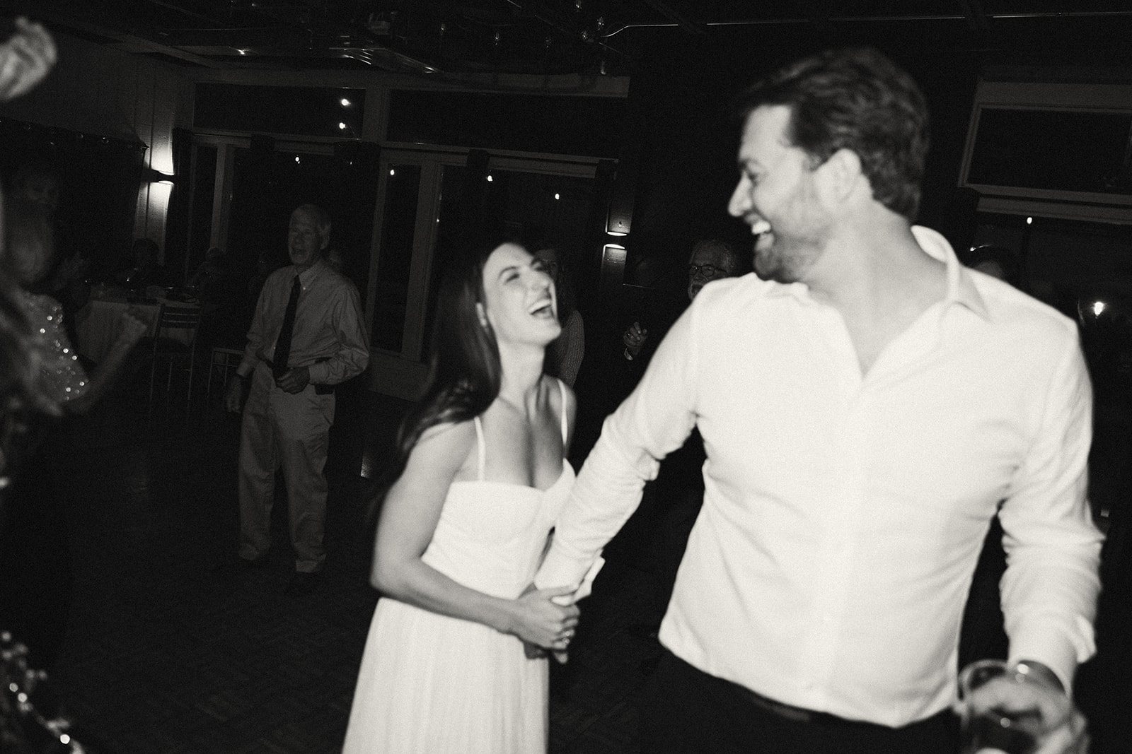 Couple smiling and dancing together in candid black and white wedding photo.