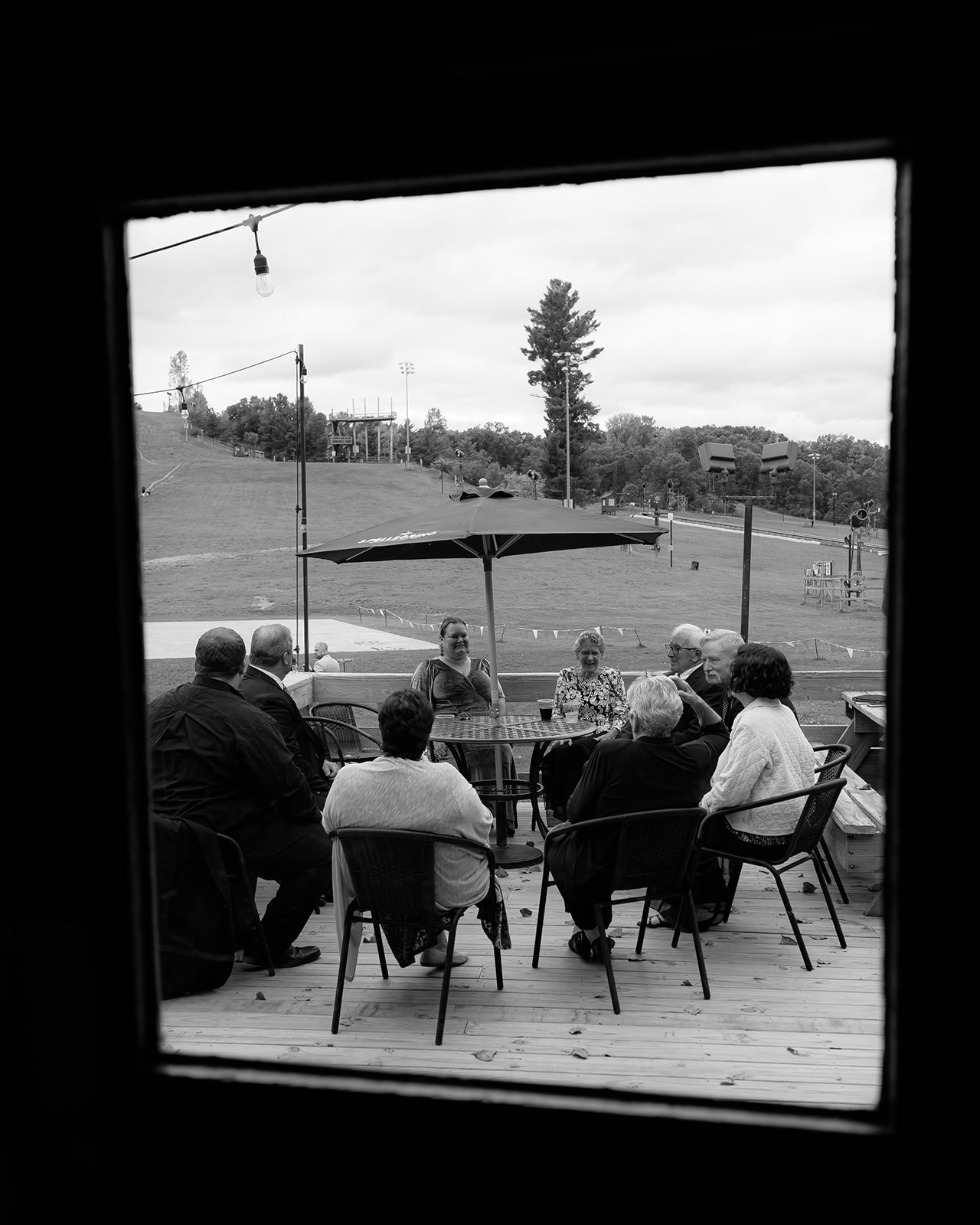 Wedding guests gathered outside on a patio, sitting together and talking during cocktail hour.