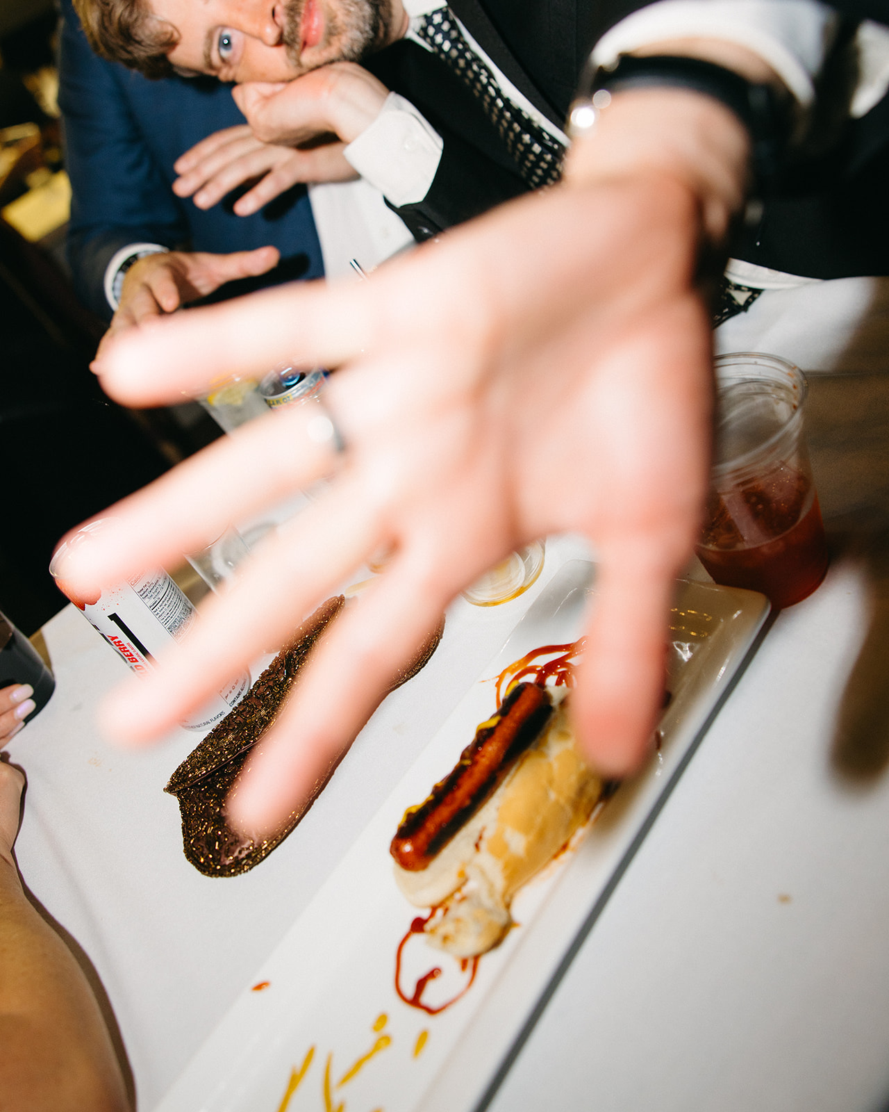 Guest grabbing a hot dog at wedding reception bar with drinks and snacks.