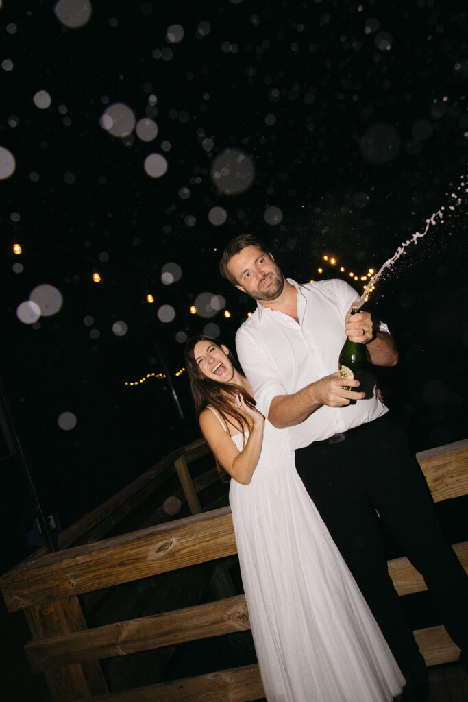 Couple celebrating with champagne spray during fun wedding night moment.