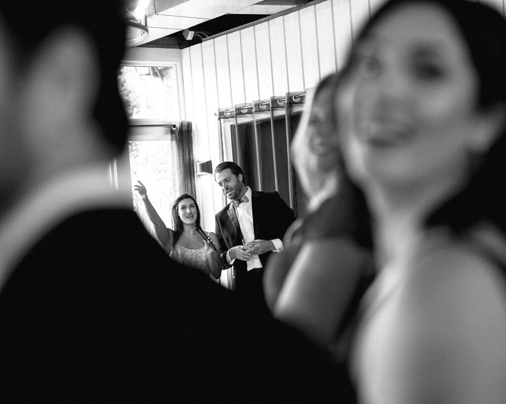 Black and white photo of a bride and groom giving a speech during their Michigan wedding captured in a documentary style.