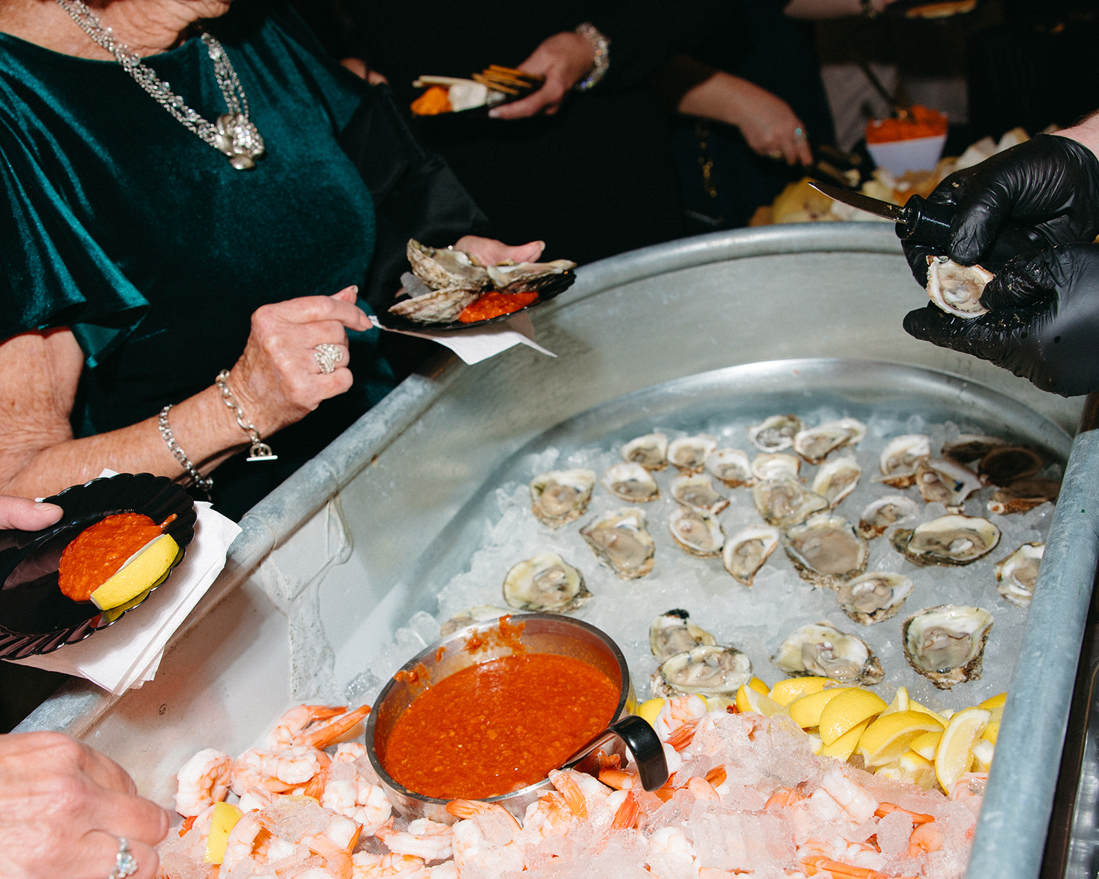 Guests serving themselves oysters and shrimp from a raw bar display during the reception.