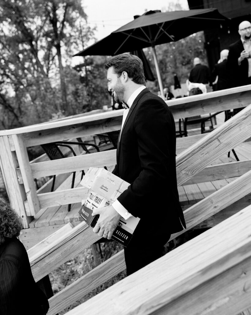 Groom carrying boxes of alcohol down the stairs for him and  guests.
